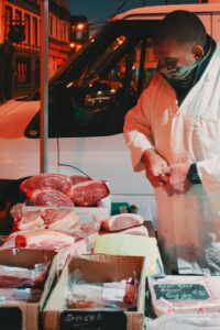 Street vendor sells fresh meats at an outdoor night market, showcasing various cuts.